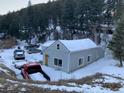 Exterior shot of the house with a truck parked in the snowy yard with tree covered hillside in the background at 1805 Hidden Valley Rd, Sedalia, CO 80135