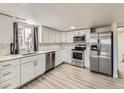 Bright kitchen features stainless appliances, white cabinets, and quartz counters by a sunny window at 5665 Niagara St, Commerce City, CO 80022