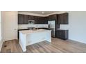 Modern kitchen featuring dark cabinets, stainless steel appliances, and a center island with a quartz countertop at 747 Raindance St, Erie, CO 80516