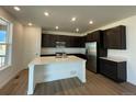 Modern kitchen with dark cabinets, stainless steel appliances, and a large island with quartz countertops at 747 Raindance St, Erie, CO 80516