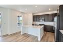 Bright kitchen with white countertops, dark cabinets, a center island, and wood flooring at 747 Raindance St, Erie, CO 80516