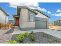 Contemporary home with a brick facade, dark trim, a red front door, and low maintenance landscaping at 9332 Bahama Ct, Commerce City, CO 80022