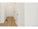 Bright hallway featuring wood-look flooring and white doors, offering a clean and modern feel at 9332 Bahama Ct, Commerce City, CO 80022