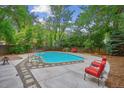 Backyard in-ground pool with diving board, chairs, concrete and stone deck, and mature trees at 629 Bellaire St, Denver, CO 80220