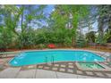 Backyard in-ground pool with diving board, hot tub, concrete and stone deck, and mature trees at 629 Bellaire St, Denver, CO 80220