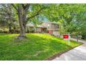 Home exterior featuring lush green lawn, landscaping, mature trees, and real estate signage at 3014 E Fremont Dr, Centennial, CO 80122