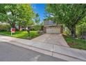 Exterior of home featuring lush green lawn, landscaping, mature trees and a two-car garage at 3014 E Fremont Dr, Centennial, CO 80122