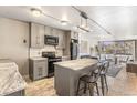 A well-lit kitchen with grey cabinets, black appliances, marble island and hardwood floors at 1050 N Corona St # 206, Denver, CO 80218