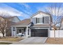 Charming two-story home with a covered porch and black garage door, set against a blue sky at 5017 Ceylon St, Denver, CO 80249