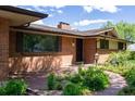 Close up of a brick house with a brown roof, featuring a front door and a large window at 962 S Beech St, Lakewood, CO 80228