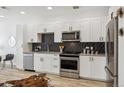 Modern kitchen with white cabinets, stainless steel appliances, and sleek black tile backsplash at 2851 W 52Nd Ave # 208, Denver, CO 80221