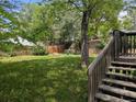Spacious, lush backyard with a wooden fence, mature trees, and a deck with wooden steps at 1251 Lee St, Lakewood, CO 80215