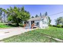 Home's exterior with new gray porch and wood railing. Features include a concrete driveway and green lawn at 6597 S State Highway 83, Franktown, CO 80116