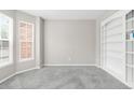 Bright living room with new gray carpet, built-in shelving and large windows at 5674 S Ingalls St, Littleton, CO 80123