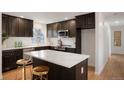 Modern kitchen features dark cabinets, stainless steel appliances, and an island with seating at 4751 S Xenia St, Denver, CO 80237