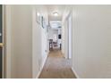 Bright hallway with neutral carpet, textured walls, and views into other rooms of the home at 18989 E Warren Dr # G303, Aurora, CO 80013