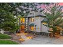 Stately home exterior with stone details, a covered entryway, mature trees, and pathway lighting at 22554 Treetop Ln, Golden, CO 80401