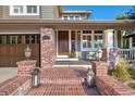 Inviting front porch with brick steps and pillars, plus space for seating at 15 Amaranth Dr, Littleton, CO 80127