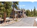 Two-story exterior featuring a stone chimney, and private drive surrounded by tall trees at 400 Upper Forest Rd, Idaho Springs, CO 80452