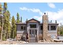 Charming gray exterior home featuring a stone chimney and inviting front porch at 400 Upper Forest Rd, Idaho Springs, CO 80452