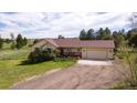 Charming ranch home with a two-car garage and front porch, surrounded by a lush green lawn and mature trees at 2464 Remington Rd, Elizabeth, CO 80107