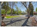 View of the house and spacious front yard with mature trees and decorative gravel at 1431 S Glencoe St, Denver, CO 80222