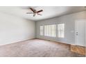 Spacious living room with carpet flooring, a ceiling fan, and large windows providing ample natural light at 169 Westin Ave, Brighton, CO 80603