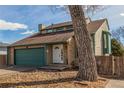 Lovely home with a green garage door, and a brick facade, complemented by mature trees and landscaping at 6758 W Louisiana Pl, Lakewood, CO 80232