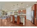 Open kitchen featuring a breakfast bar, stainless steel appliances, and hardwood floors at 8054 E 152Nd Dr, Thornton, CO 80602