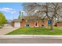 Charming brick home with a lush green lawn, red front door, and inviting blue Adirondack chairs at 4544 W 65Th Ave, Arvada, CO 80003