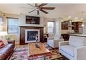 Elegant living room with fireplace, ceiling fan, hardwood floors, and view of the kitchen at 13713 Raritan Ln, Broomfield, CO 80023