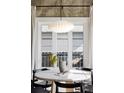 Close-up of round dining table with modern light fixture and bright light from large windows at 3927 N Cook St, Denver, CO 80205