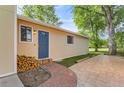 Exterior side view showcasing a blue front door, with an inviting brick walkway and lush green lawn at 6396 Twin Lakes Rd, Boulder, CO 80301