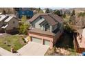 Aerial view of home with green siding, brick facade, three car garage, and manicured lawn at 16652 W Archer Ave, Golden, CO 80401