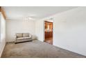 Cozy living room featuring neutral carpet, white walls, and a glimpse into the kitchen at 1175 Xanthia, Denver, CO 80220