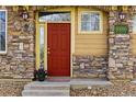 Close-up of a red front door with stone trim, house number, and decorative flower pot at 9980 W Jewell Ave # B, Lakewood, CO 80232