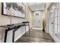 Inviting entryway with dark wood floors, console table, modern art, and a glass paneled door at 10104 Nadine Ave, Parker, CO 80134