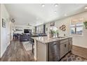 Modern kitchen island featuring granite countertops and stainless steel dishwasher, seamlessly flowing into the living area at 803 William Way, Brighton, CO 80603