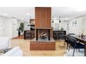 Open concept living room featuring a brick fireplace and wood floors at 1330 Olive St, Denver, CO 80220