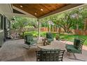 Covered patio with outdoor seating, view of the backyard with mature landscaping and privacy fence at 6128 S Coventry E Ln, Littleton, CO 80123
