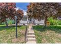 Charming home with white siding and a well-manicured lawn, framed by vibrant, mature trees. A welcoming entrance at 2845 Eaton St, Wheat Ridge, CO 80214