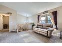 Bright living room with a plush sofa, large window, and staircase leading to upper level at 12425 Bellaire Dr, Thornton, CO 80241
