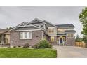Beautiful two-story home featuring brick accents, manicured lawn, and lush landscaping for great curb appeal at 6401 S Millbrook Way, Aurora, CO 80016