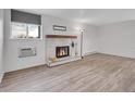 Cozy living room with a white brick fireplace, wood mantel, and light wood-look floors at 17505 E Mansfield Ave # 1412R, Aurora, CO 80013