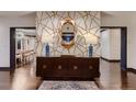 Elegant foyer with geometric wallpaper, stylish console table, and dark-stained hardwood floors at 6483 S Prince St, Littleton, CO 80120