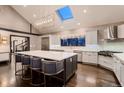 Modern kitchen with a large island, skylight, stainless steel appliances, and designer lighting fixtures at 6483 S Prince St, Littleton, CO 80120