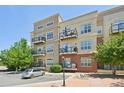 Exterior shot of an apartment building with beige siding, multiple balconies, and street parking at 5677 S Park Pl # 311A, Greenwood Village, CO 80111