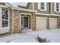 Front entrance of a house with brick and siding, a two-car garage and snowy ground at 223 Durham Ct, Castle Pines, CO 80108