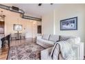 Comfortable living room with a neutral colored sofa, accent rug, and a view into the dining area at 10111 Inverness Main St # 228, Englewood, CO 80112