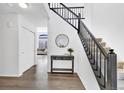 Inviting entryway features hardwood floors, a staircase with black railings, and a decorative table with a round mirror above it at 275 S Pembrook St, Castle Rock, CO 80104